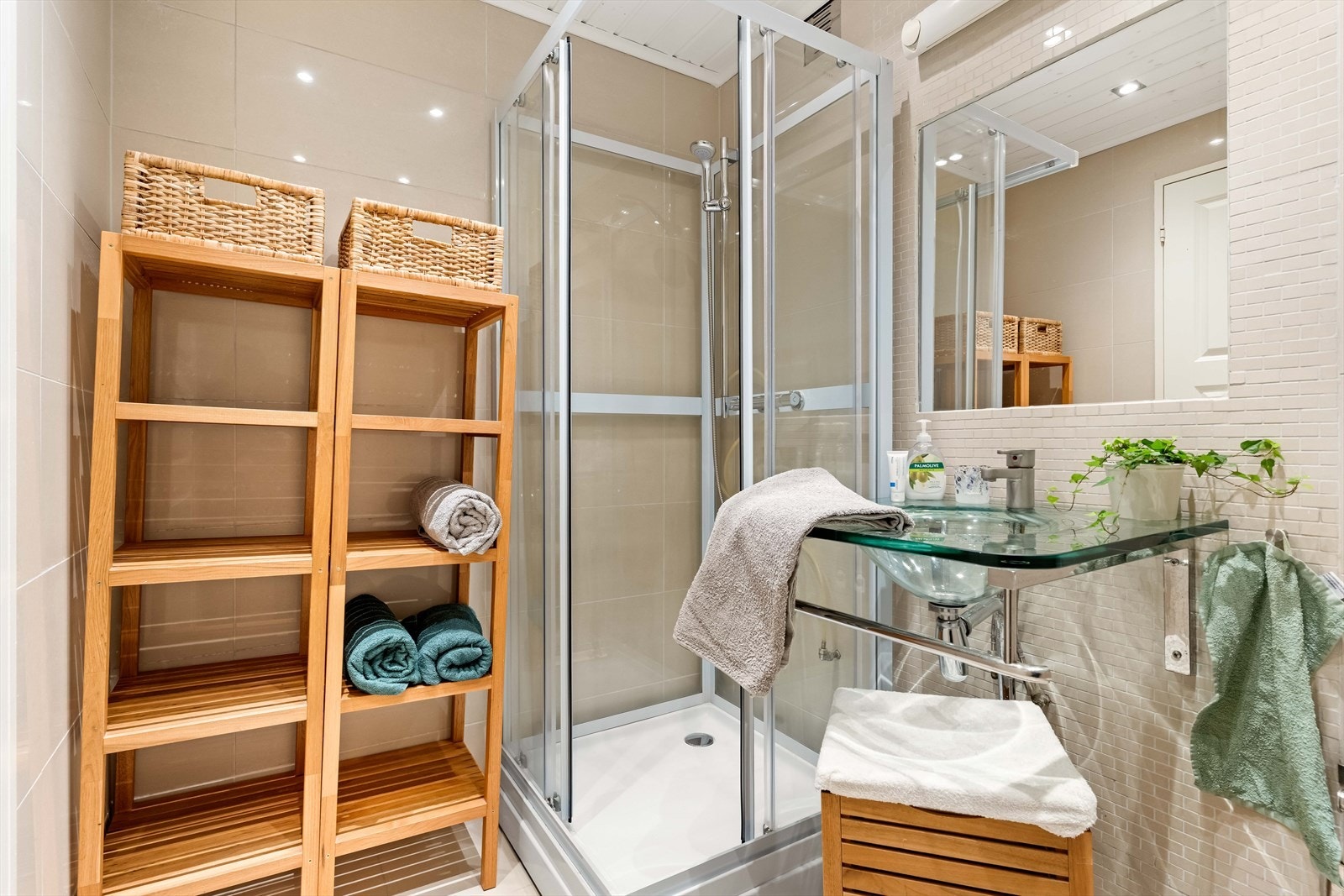 Badet har servant i glass med 1 greps servantbatteri, speil og lys, dusj på gulv med dusjvegger i glass og gulvstående toalett. Galleribilde