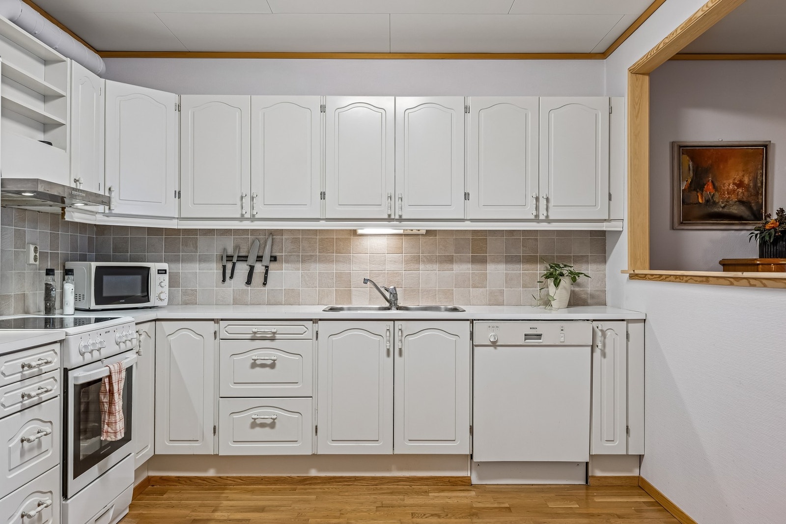 Et lyst kjøkken med god oppbevaringsplass og praktisk benkeplass. Galleribilde