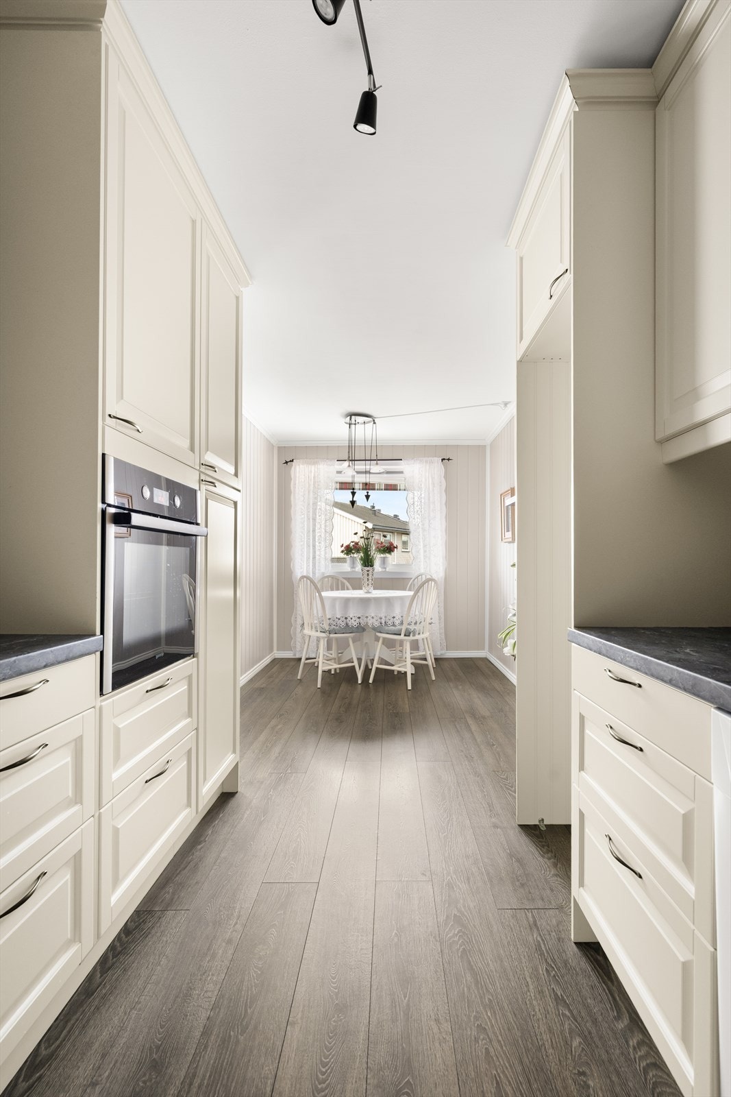 Hvite profilerte fronter og laminert benkeplate gir kjøkkenet et klassisk preg. Galleribilde