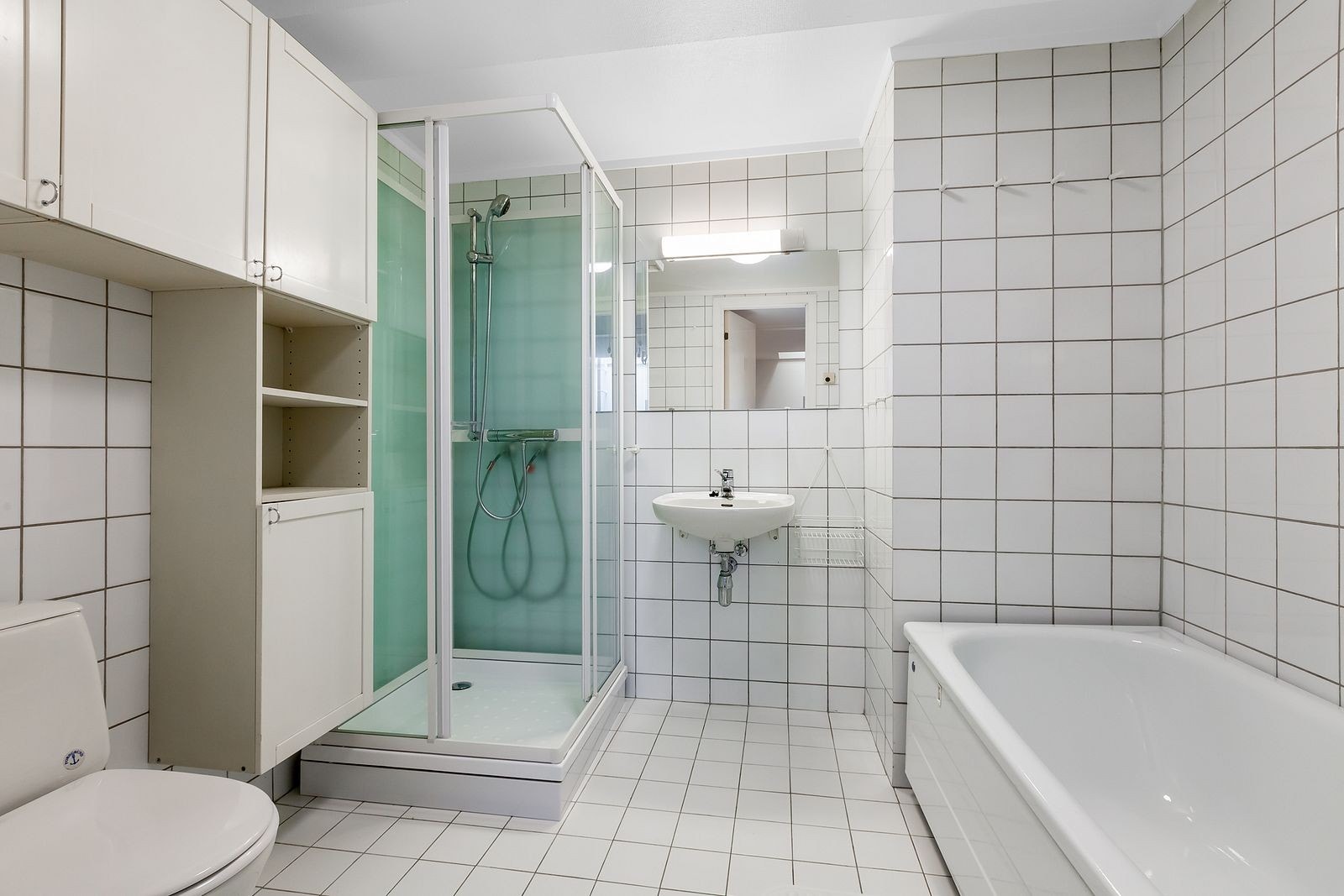 Flislagt bad med nytt dusjkabinett, badekar, servant, toalett og skapinnredning. Eget vaskerom. Galleribilde