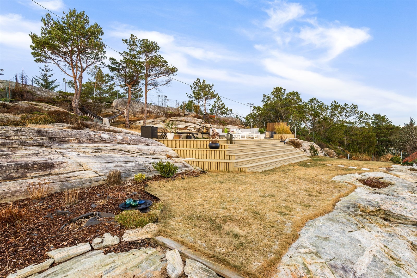 Tomten er opparbeidet med plen, beplantning og terrasseplatting. Galleribilde