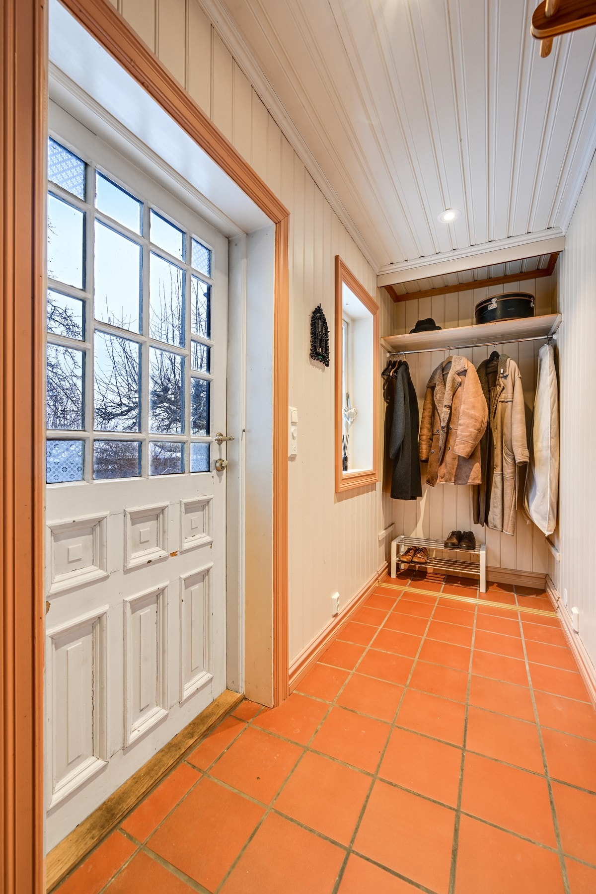 Eget inngangsparti på østsiden av huset, med flislagt entré og stativ for klesoppheng Galleribilde