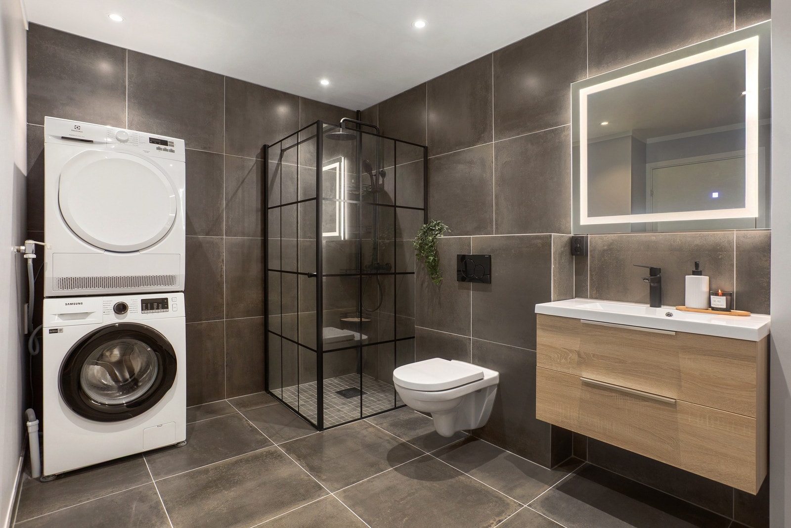 Pent flislagt bad med gulvvarme fra 2021. Innredet med dusjhjørne, vegghengt toalett, servantskap med speil med integrert belysning, samt opplegg for vaksemaskin og tørketrommel Galleribilde