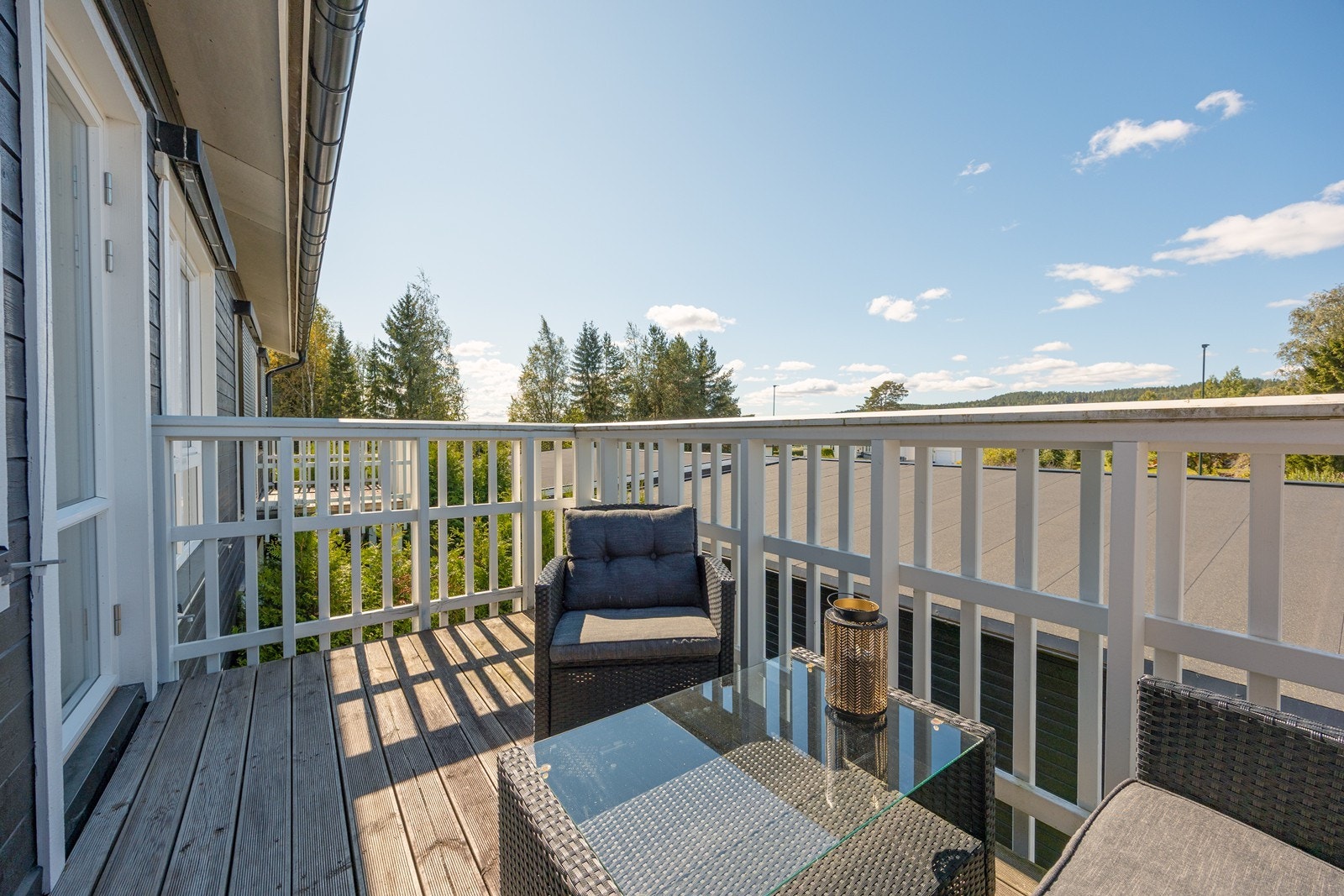 Balkongen har tredekke, hvitmalt rekkverk og moderne utebelysning. Galleribilde