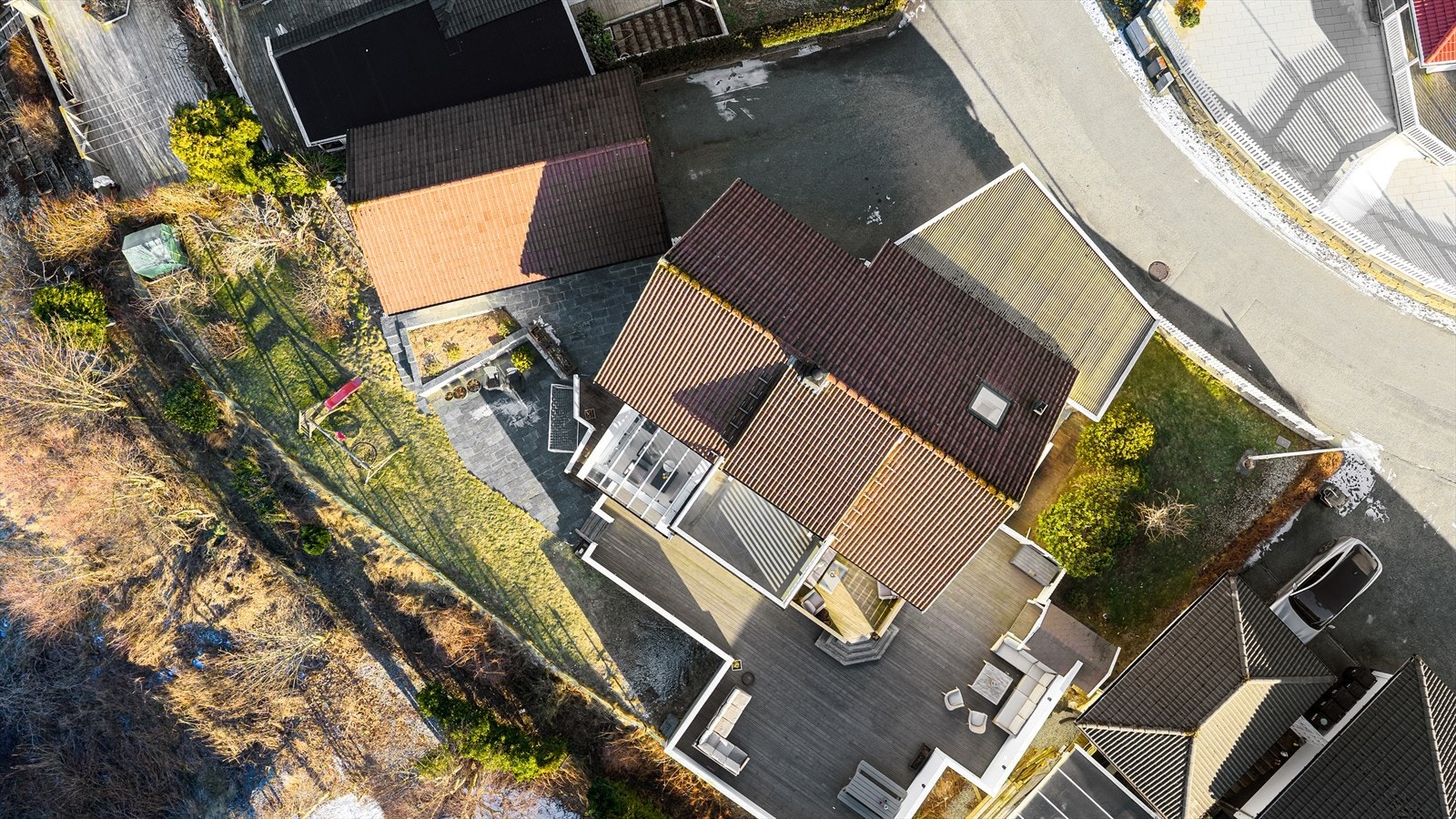 Tomten er meget pent opparbeidet med asfaltert gårdsplass, fliser ved inngangsparti, skifereterrasse, stor treterrasse med levegger og flott hage med diverse beplantning Galleribilde