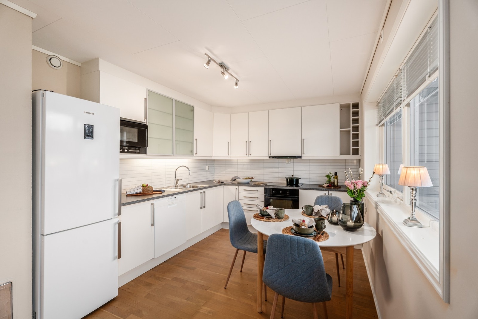 Kjøkken med takhøy innredning. Legg merke til belysning på underside av overskap og smarte hyller til eksempelvis kokebøkene dine. Galleribilde