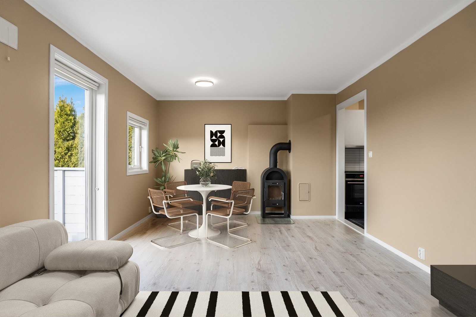 Stuen har god plass til både sofagruppe og spisebord, og er utstyrt med vedovn. Bildet er digitalt møblert Galleribilde