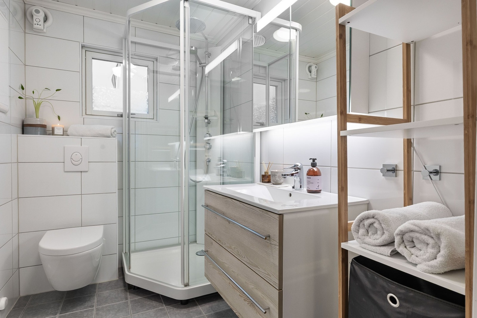 Badet har dusjkabinett, vegghengt toalett og servant med underskap. Galleribilde