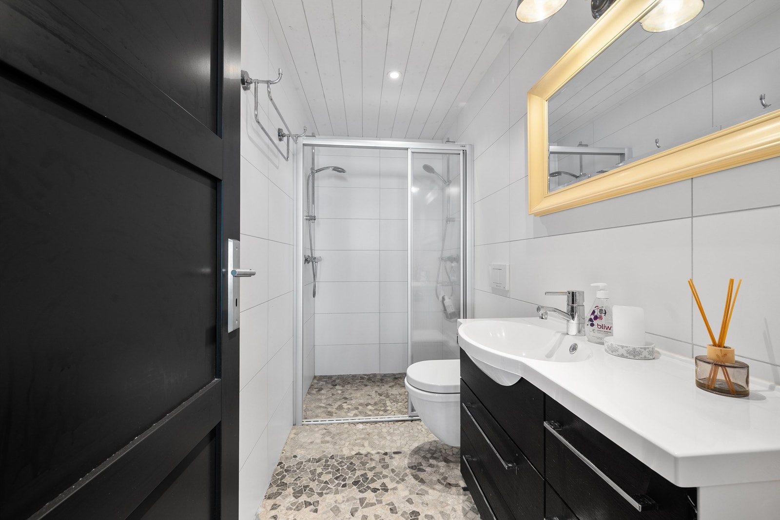 Badet i 1.etg er innredet med flislagt gulv med varmekabler, flislagte vegger, servant med skuffer, wc og dusjnisje med glassdør Galleribilde