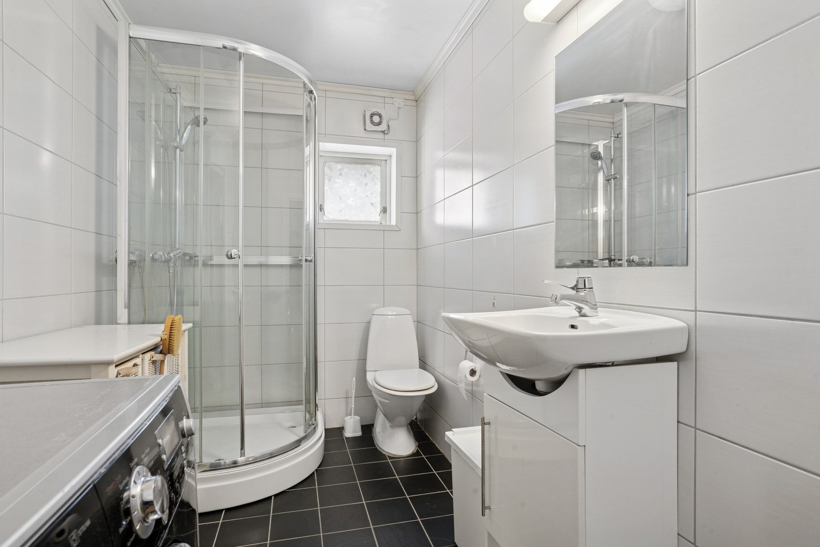 Baderommet i utleiedelen byr på flislagte overflater, vegghengt servant og dusjkabinett. Galleribilde