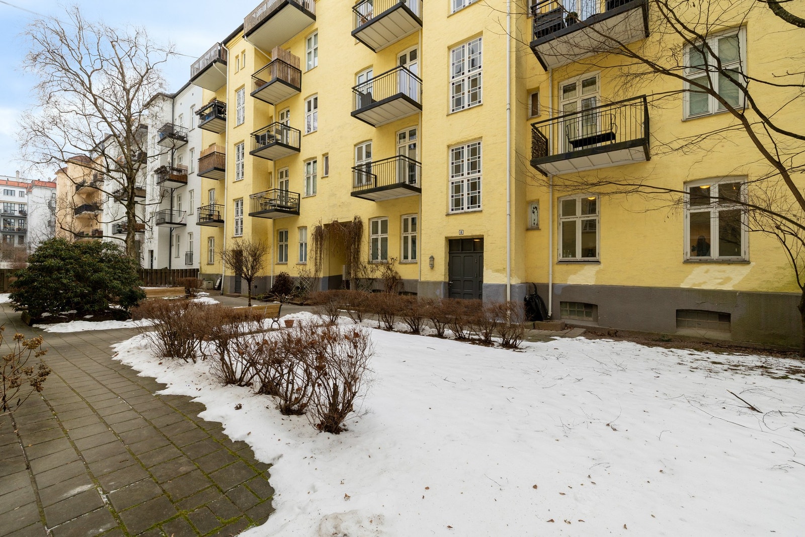 Pent opparbeidet gårdsrom med sittebenker og grønne omgivelser. Galleribilde