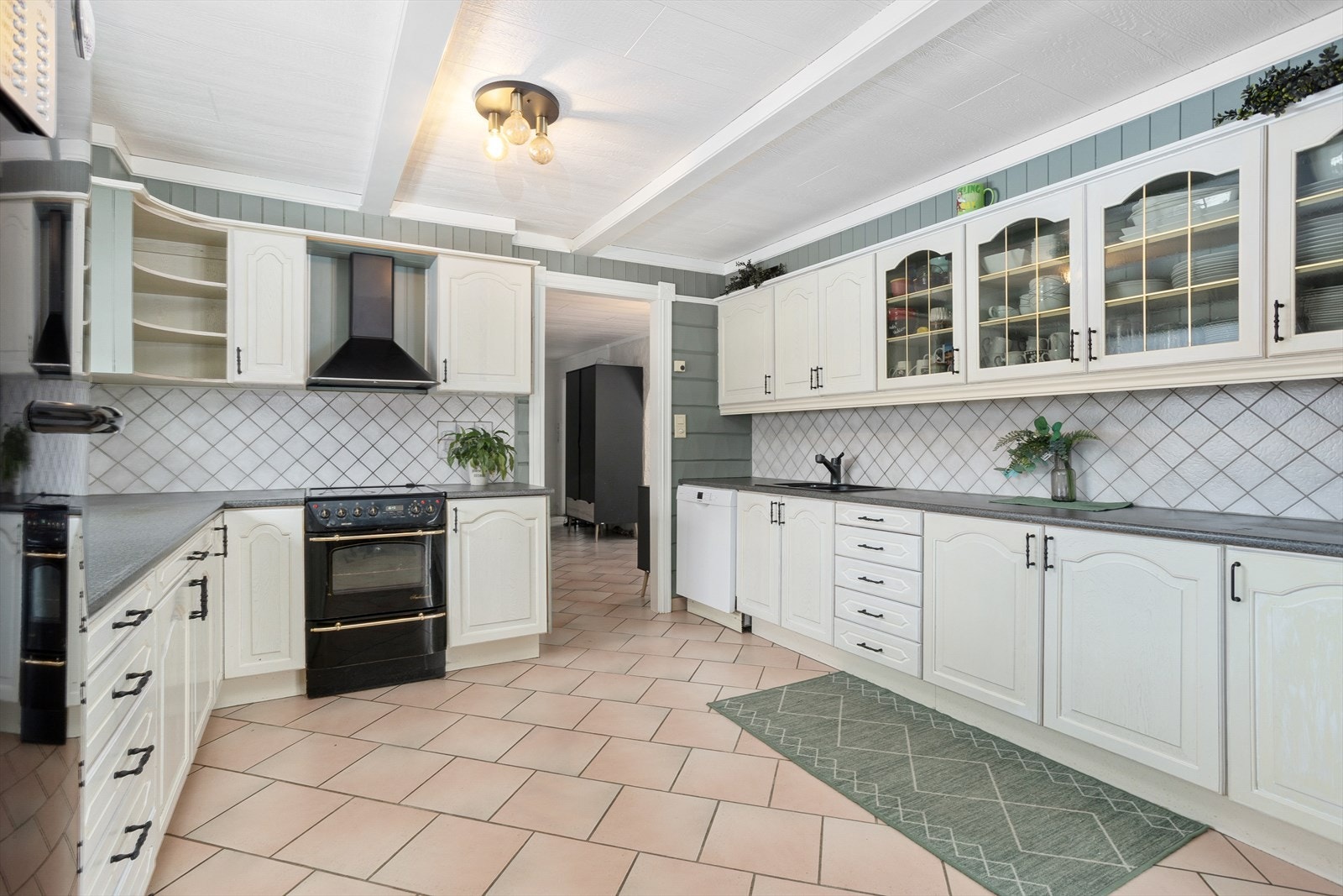 Kjøkkenet har profilert innredning og laminat benkeplater, samt fliser på veggen over benken. Galleribilde