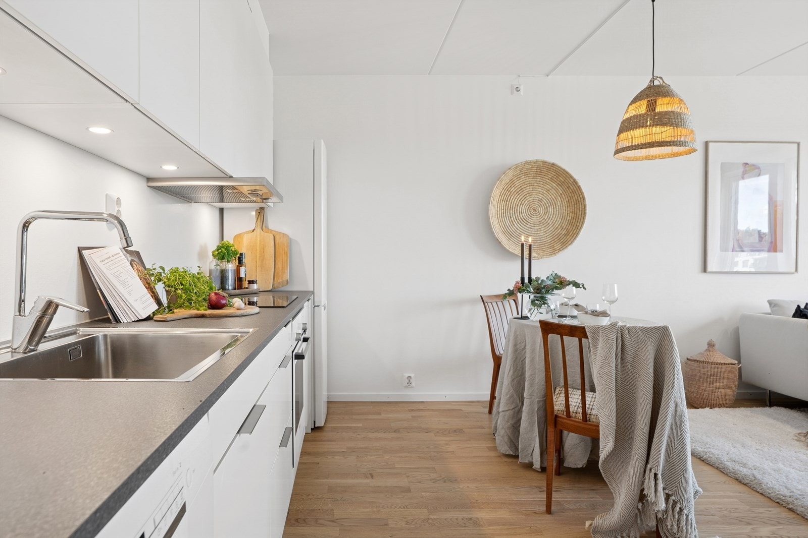 Innredningen har hvite, glatte fronter, en laminert benkeplate og en nedfelt oppvaskkum i rustfritt stål. Galleribilde