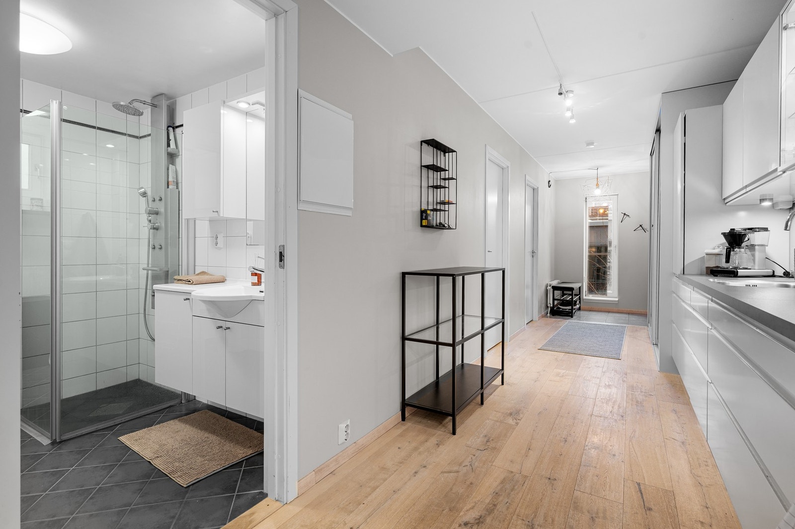 Kjøkkenet strekker seg langs den ene veggen og er av en god størrelse. Hvit kjøkkeninnredning med glatte fronter og smarte oppbevaringsløsninger. Galleribilde