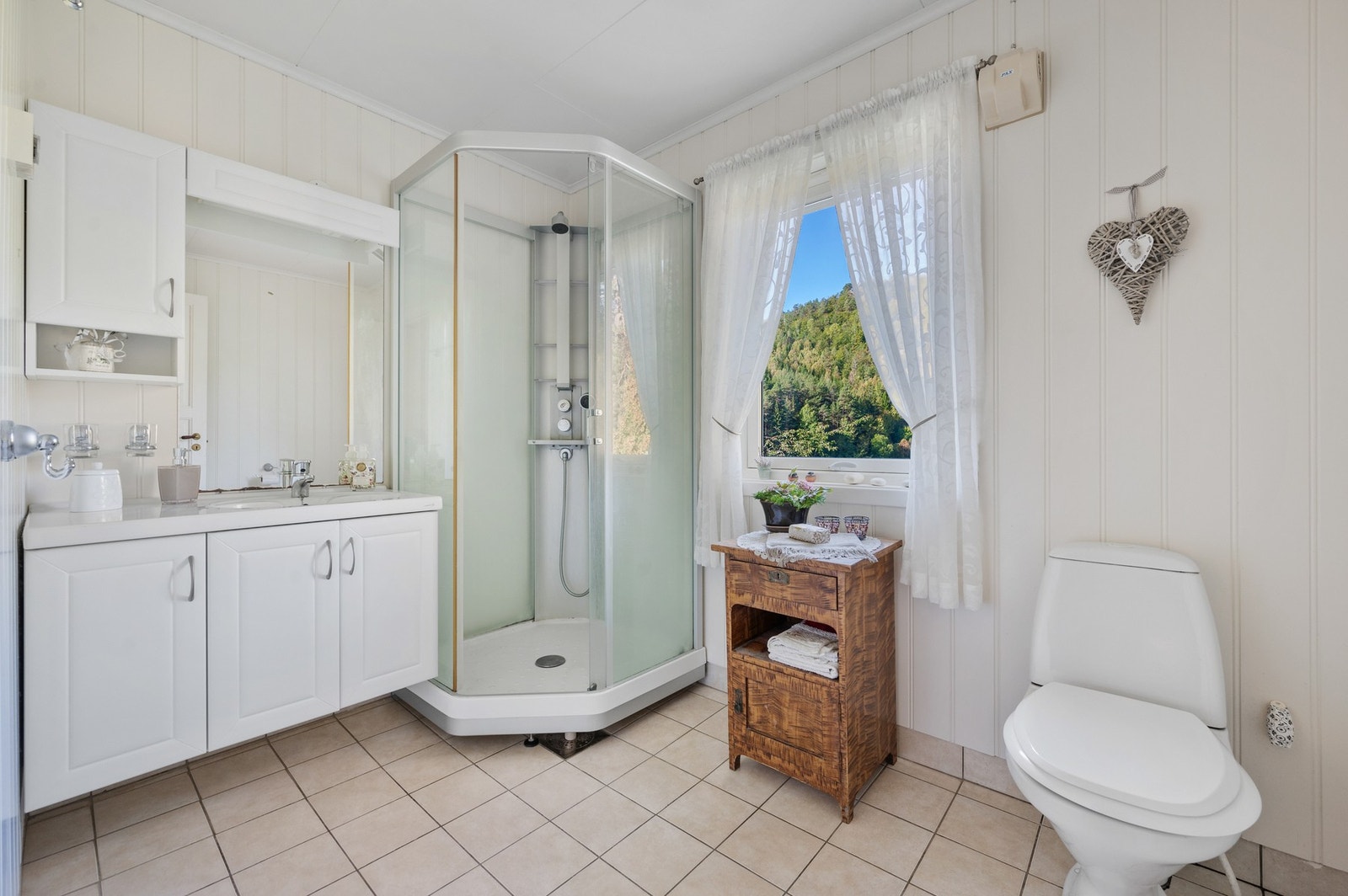 Flislagt baderom med toalett, servant og dusj kabinett. Det er varmekabler i gulvet. Galleribilde