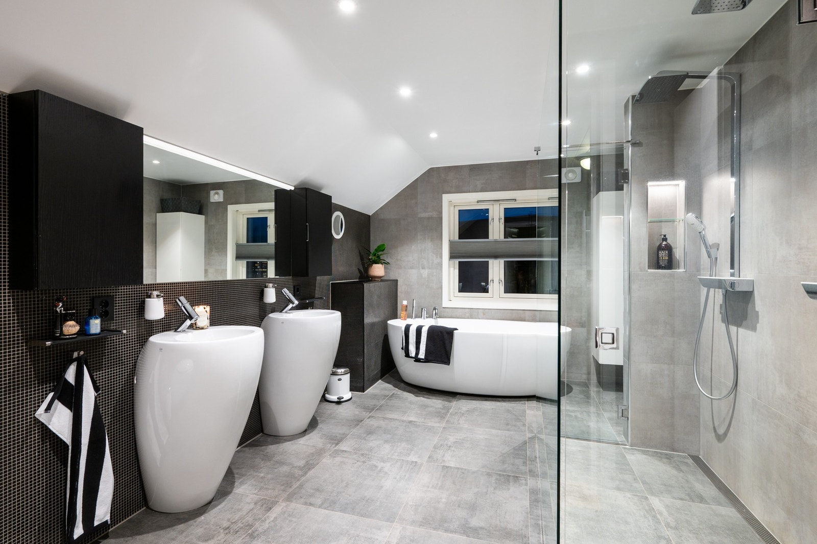 Badet er på hele 12,5 kvm. og inneholder dobbelt servant, speil, god skapplass, badekar, vegghengt toalett, dobbel dusj og håndklevarmere. Det er også en praktisk skittentøyssjakt som fører direkte ned til vaskerommet Galleribilde