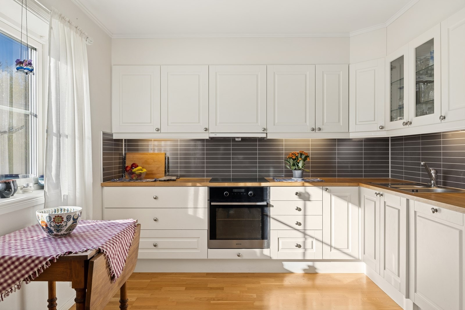 Kjøkkenet er innredet med profilerte fronter og heltre benkeplate, som gir et tidløst og lunt preg. Det er integrert platetopp, stekeovn og oppvaskmaskin, mens kjøl/fryseskap er frittstående Galleribilde