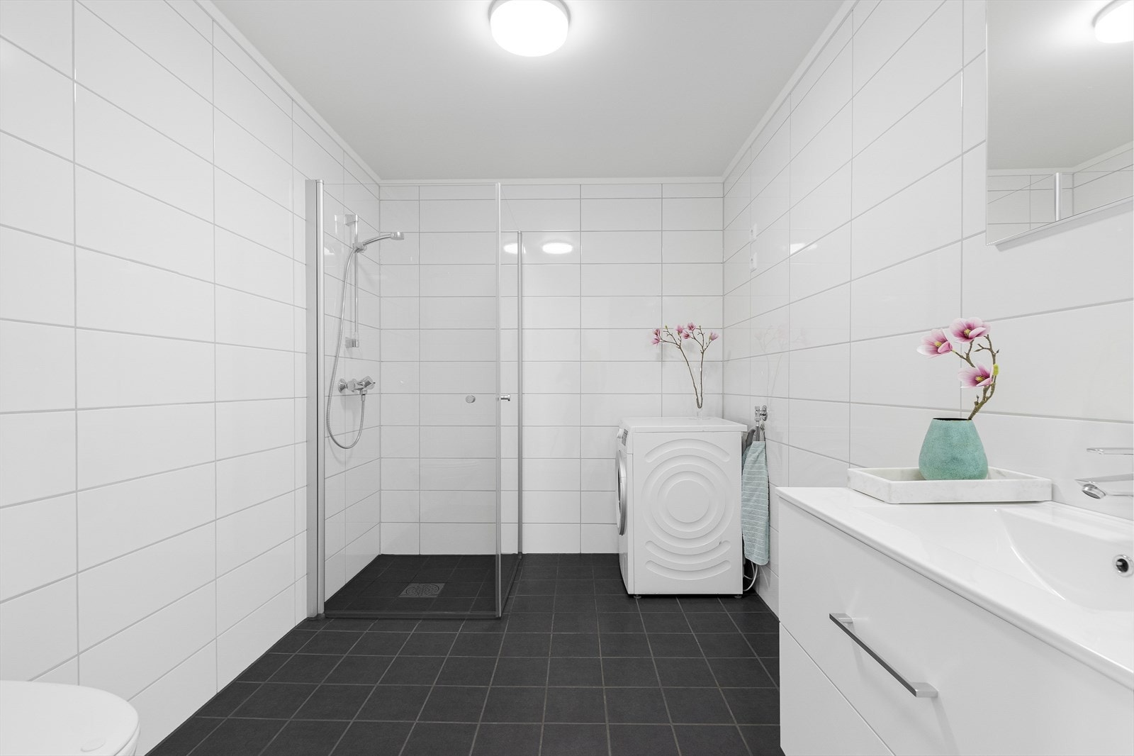 Moderne bad med dusj, vegghengt WC, innredning m/vask og opplegg for vaskemaskin. Galleribilde