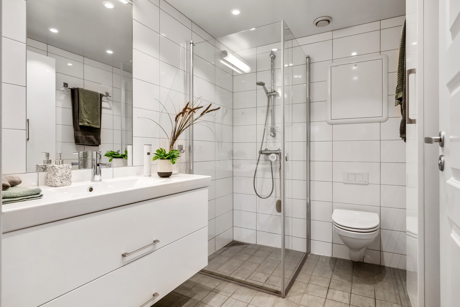 Badet har innredning med nedfelt servant, veggmontert toalett og dusjvegger/hjørne. Galleribilde