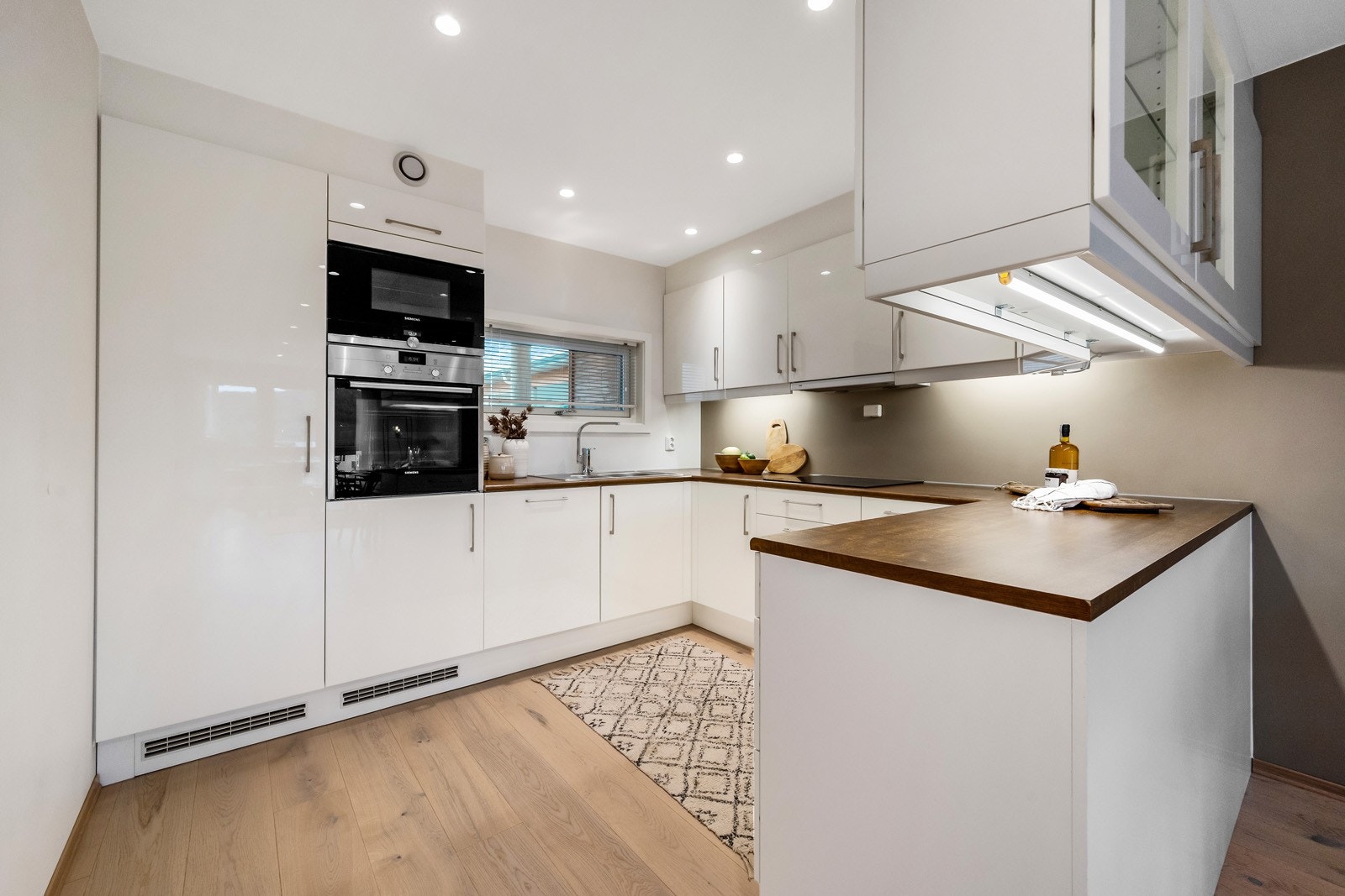 Kjøkkenet har innredning med hvite glatte fronter. Benkeplaten er av laminat. Galleribilde