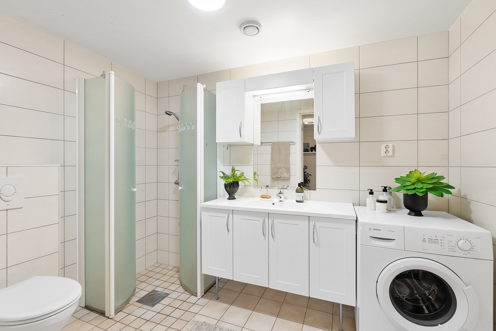 Stort flislagt bad. Vegghengt wc, dusjhjørne og opplegg for vaskemaskin/tørketrommel. Galleribilde