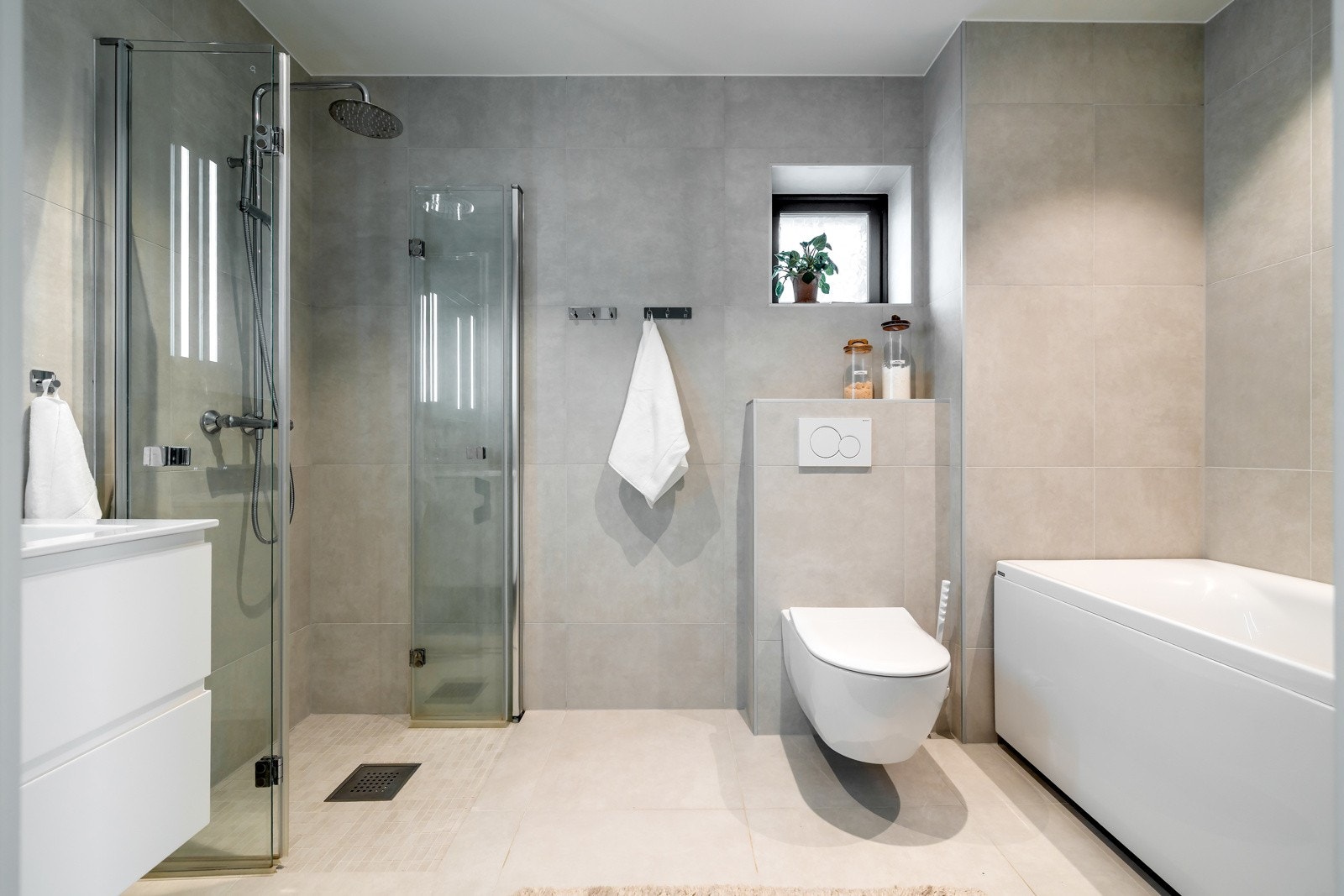 Badet i 1. etasje ligger i tilknytning til de to soverommene og fremstår som et stilrent og moderne rom med lyse fliser på både gulv og vegger. Galleribilde