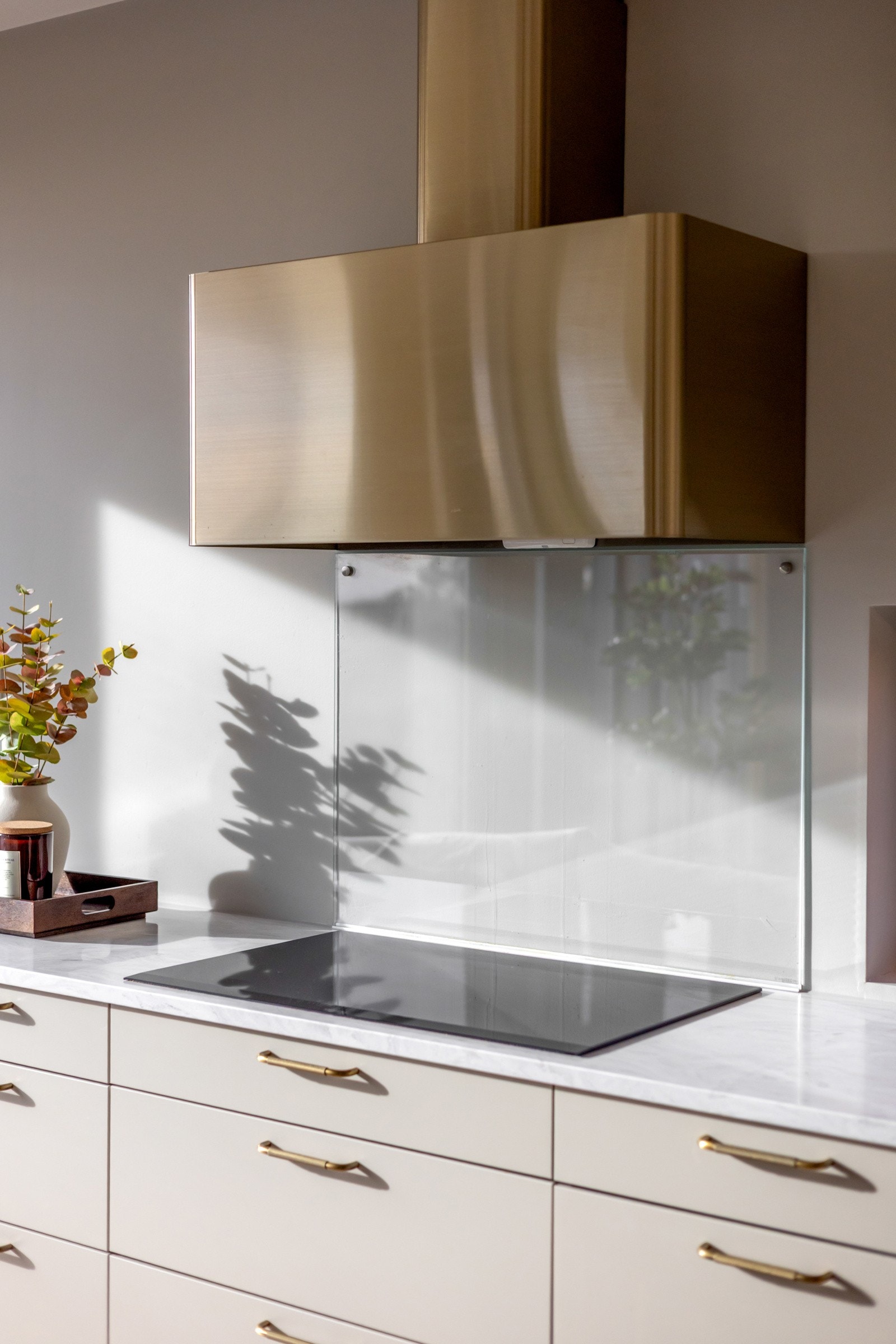 Ventilator fra RørosHetta i børstet messingutførelse harmonerer elegant med håndtak og armatur. Det er også montert en glassplate over koketoppen Galleribilde