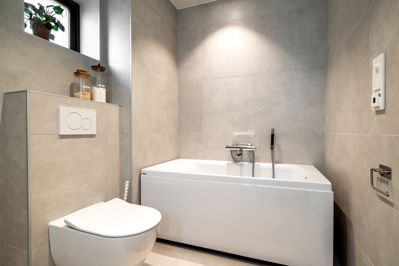 Rommet er utstyrt med dusjhjørne med glassdører, badekar, vegghengt toalett og servantinnredning med skuffer for oppbevaring. Galleribilde