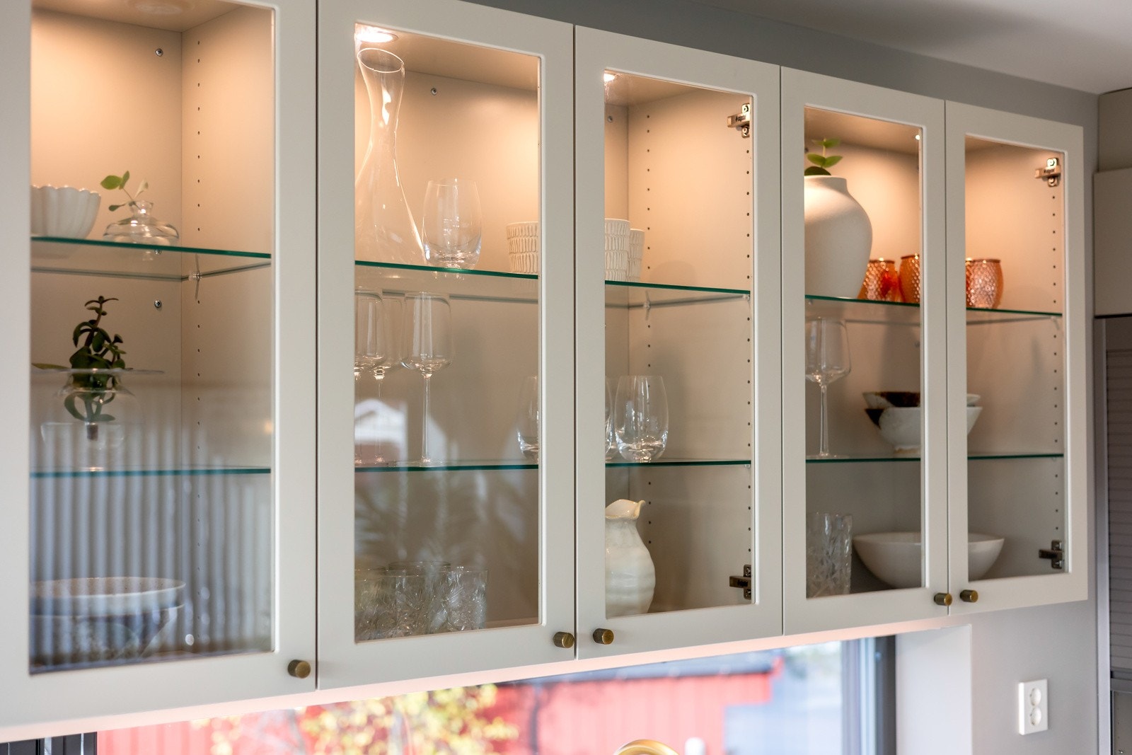 Overskap med glassdører og innvendig belysning gir en luftig og eksklusiv følelse, samtidig som det gir god plass til oppbevaring. Galleribilde