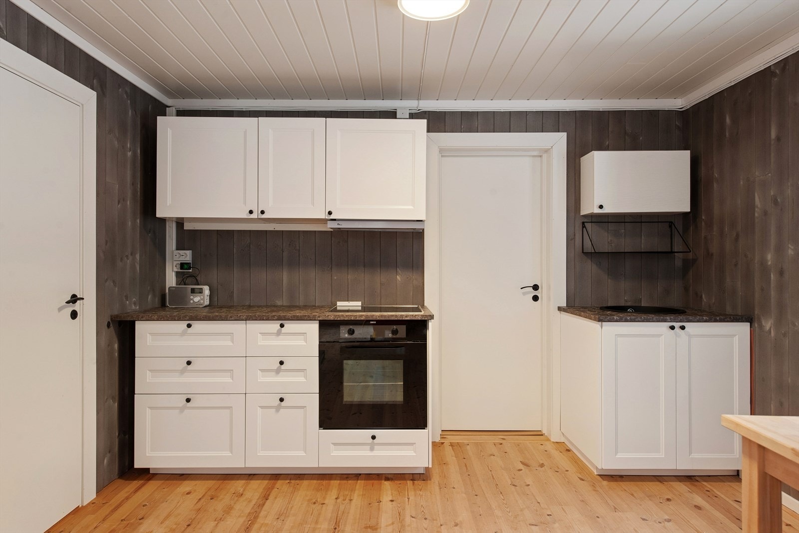 Kjøkkeninnredningen er pent utført med hvite, profilerte fronter og laminert benkeplate med nedfelt komposittkum. Galleribilde