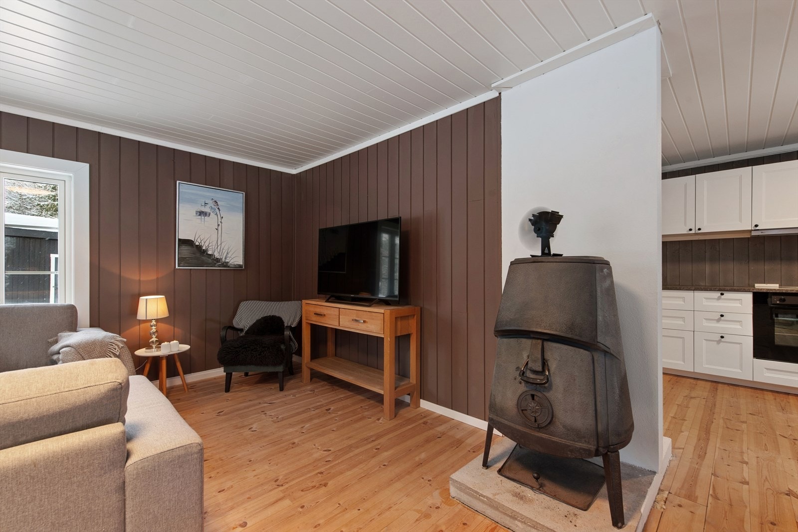 Lakkert tregulv og malt panel er gjennomgående, noe som gir et helhetlig og lunt uttrykk. Galleribilde