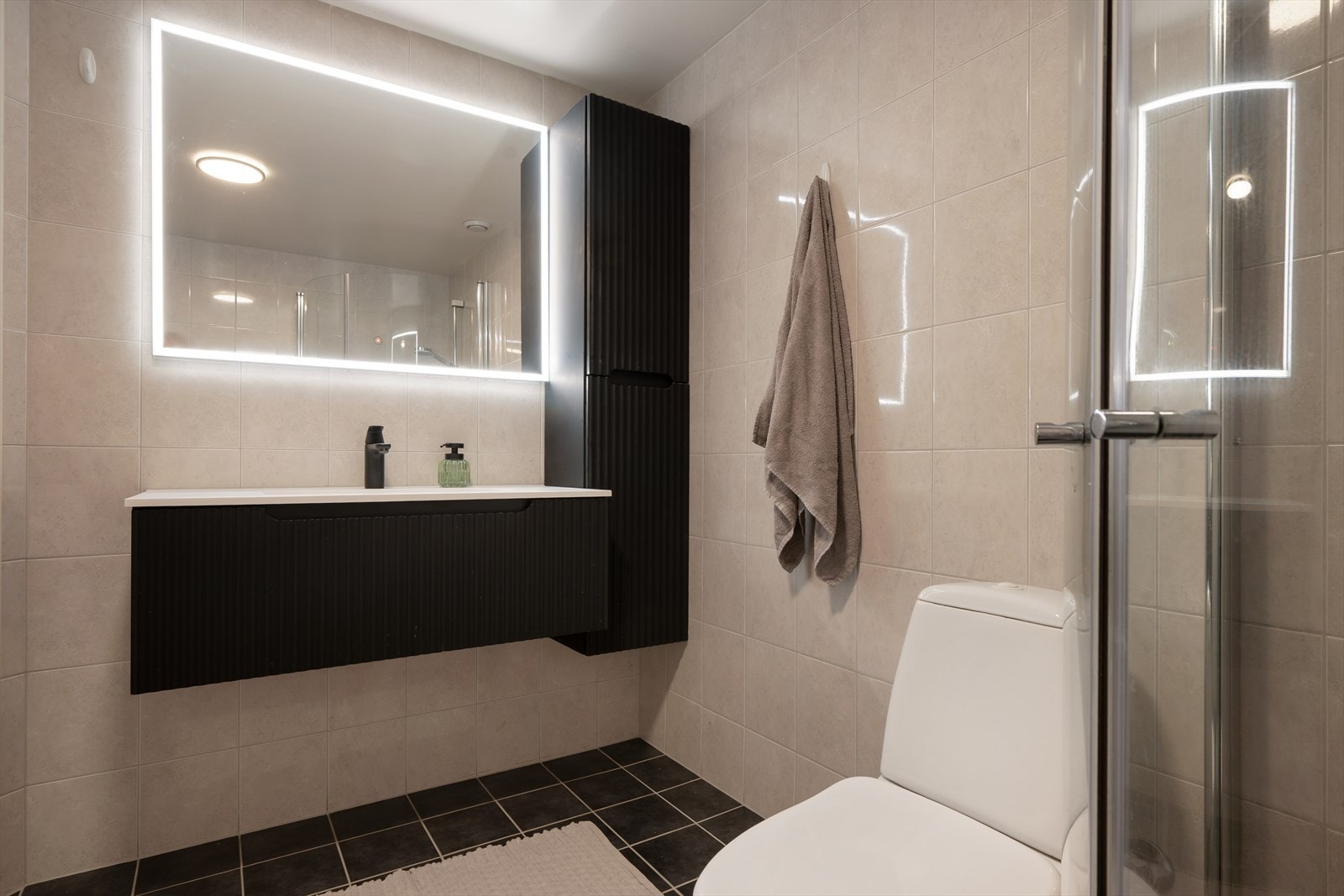 Heldekkende servant og speil med belysning kompletterer baderomsinnredningen. Galleribilde