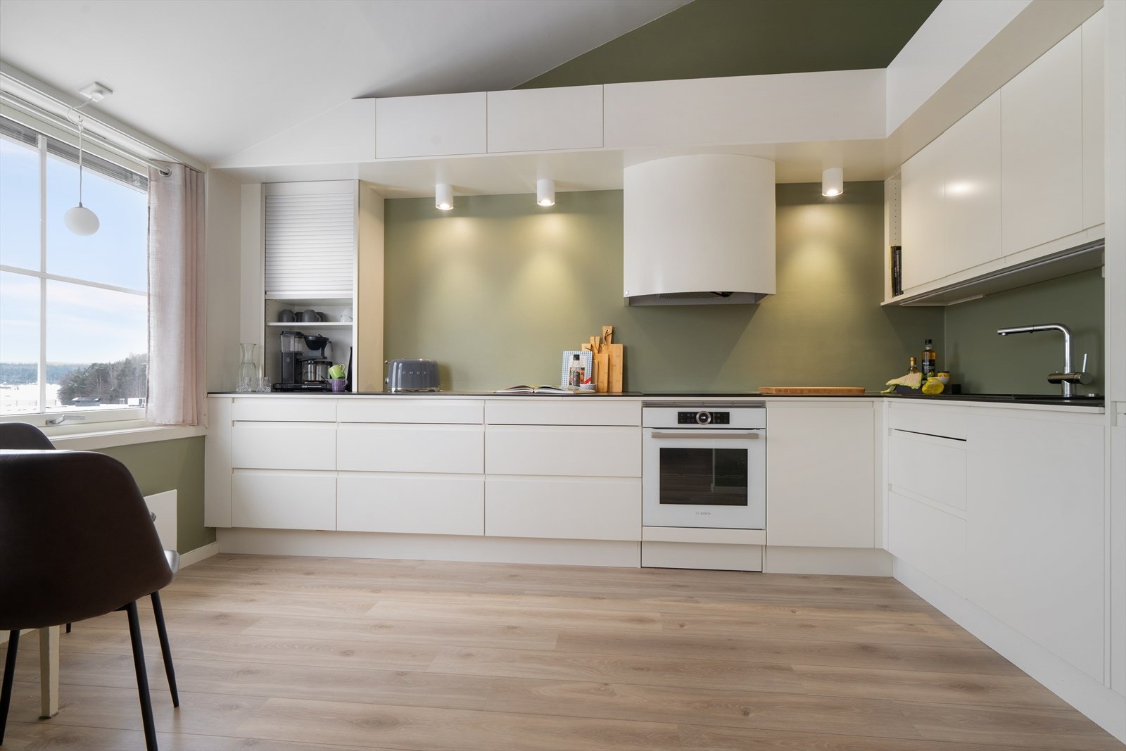 Overskapene gir ekstra lagringsplass, og den åpne planløsningen skaper en romslig kjøkkensone. Galleribilde