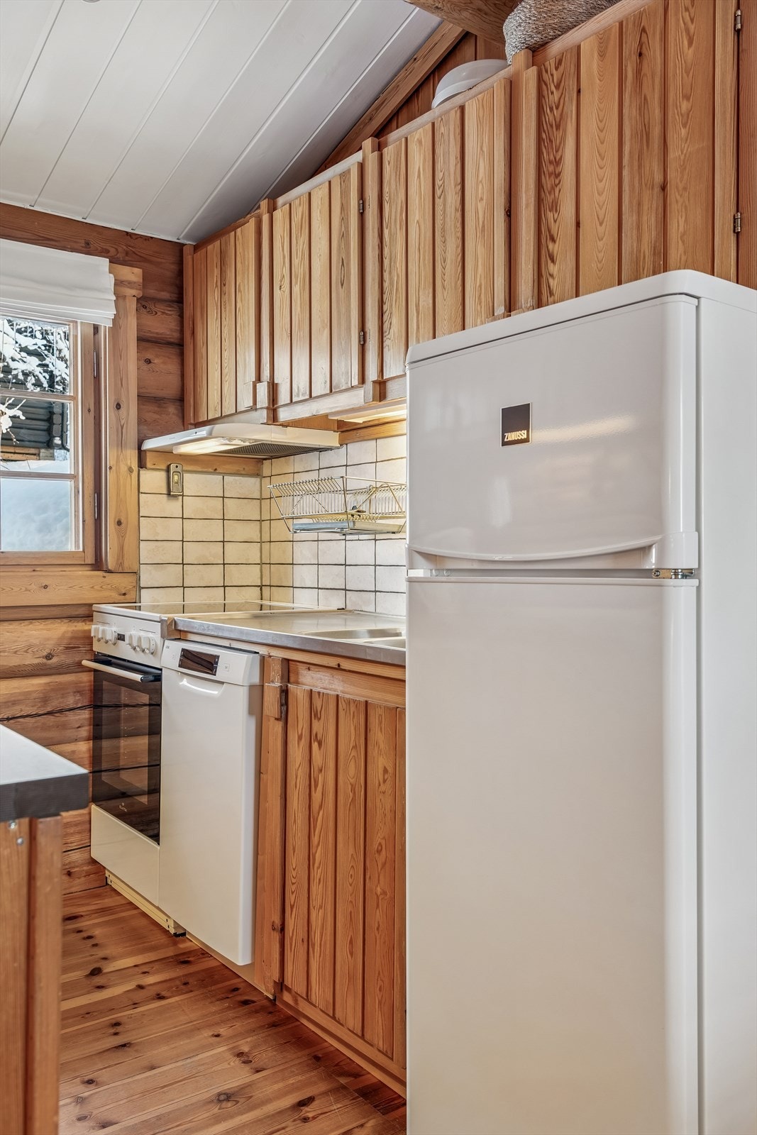 Praktiske fliser på vegg over benk, heldekkende benkebeslag og åpen plass for hvitevarer. Galleribilde