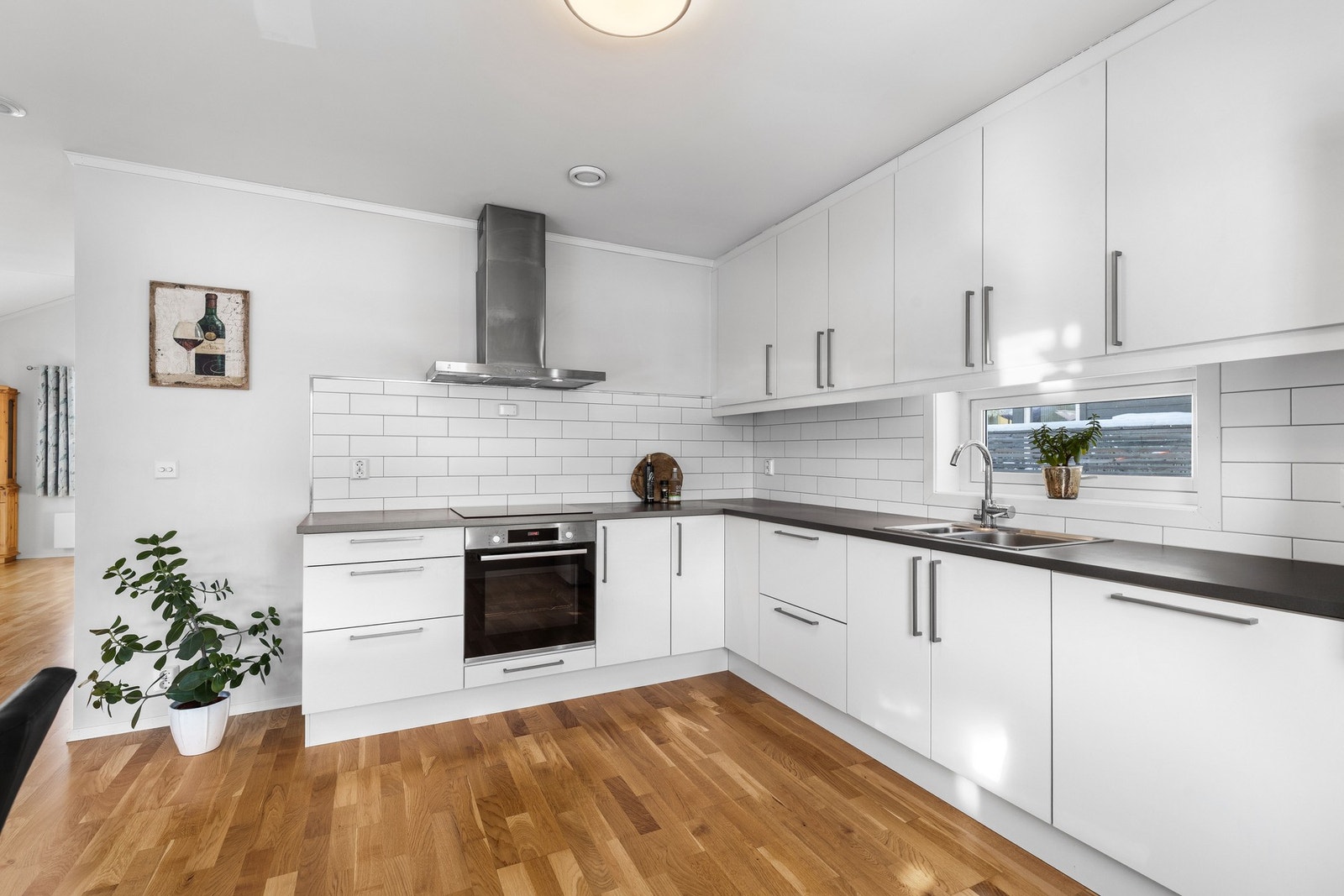 Det er fliser mellom over- og underskap, integrert oppvaskmaskin samt komfyr og platetopp. Galleribilde