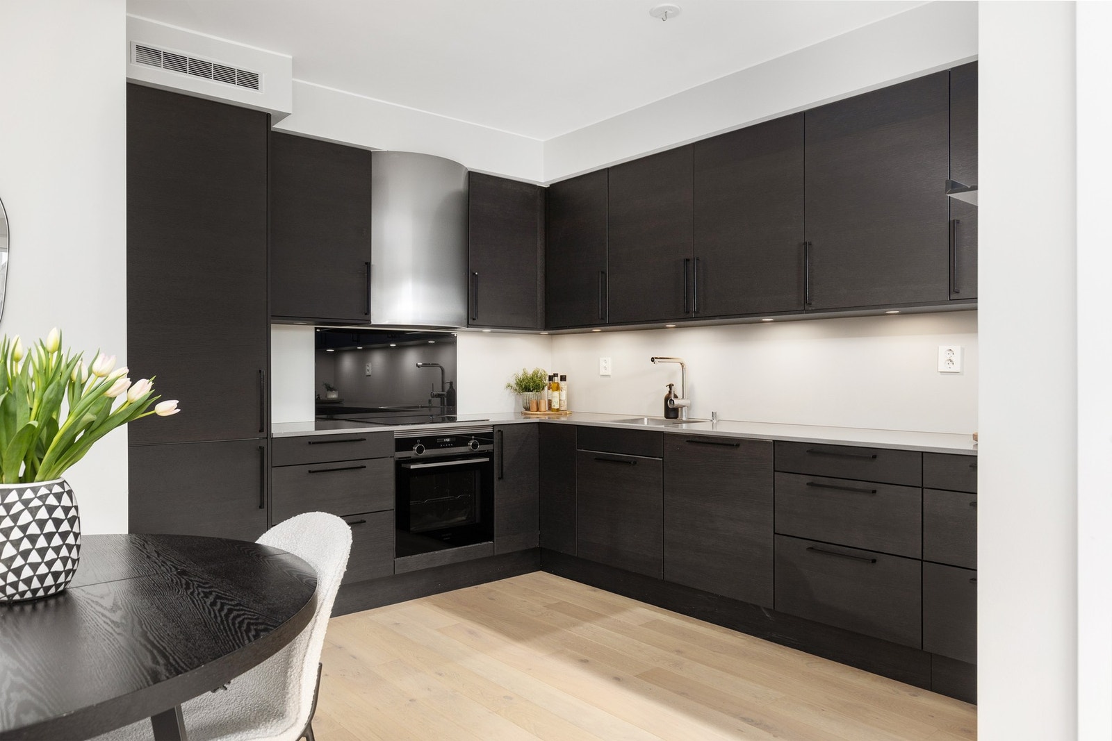 Tidsmessig kjøkkeninredning med mørkfinérte fronter. Gode oppbevaringsmuligheter i skuffer og skap. Galleribilde