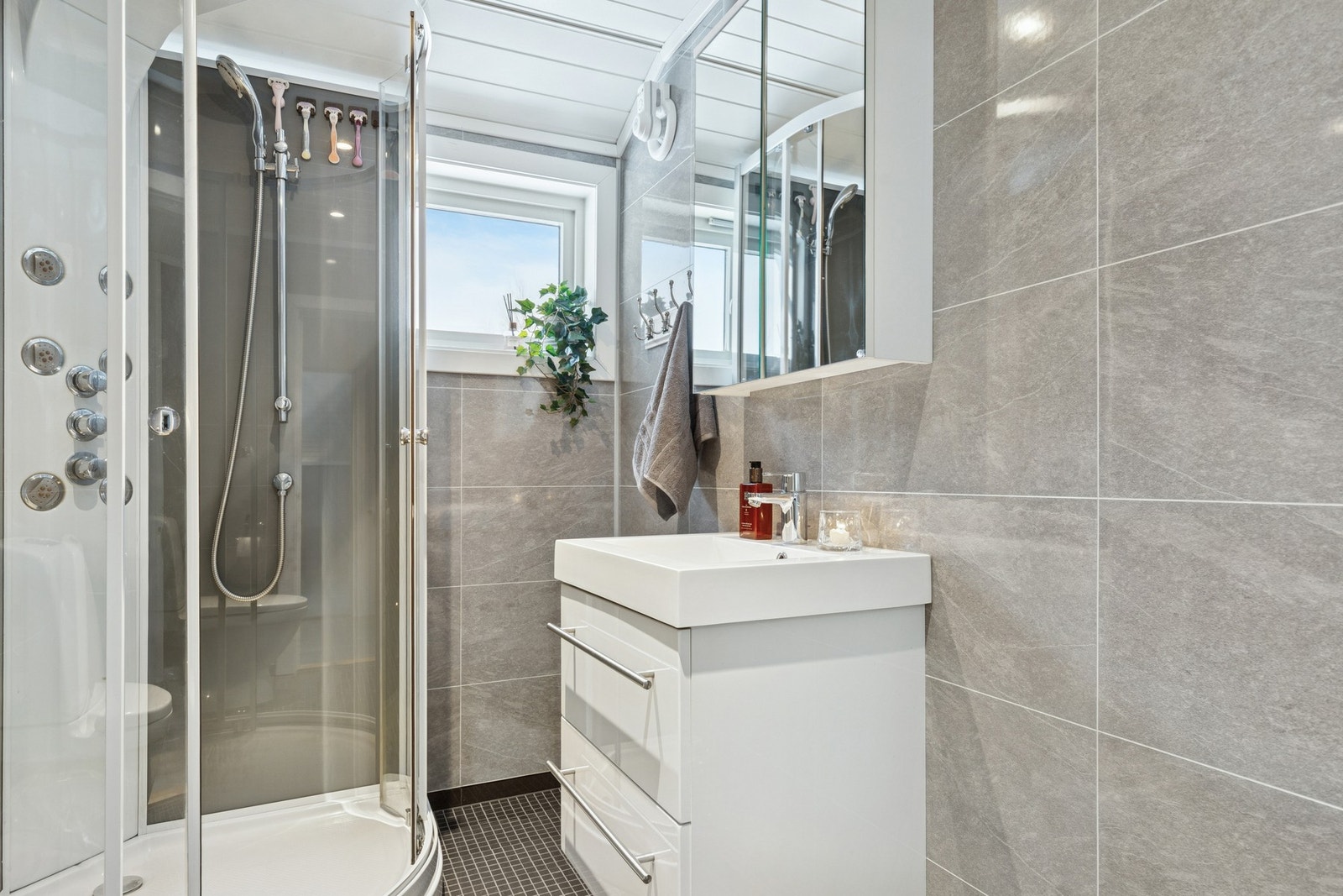 Baderommet er utstyrt med vegghengt servant, dusjkabinett og overskap med speil. Galleribilde