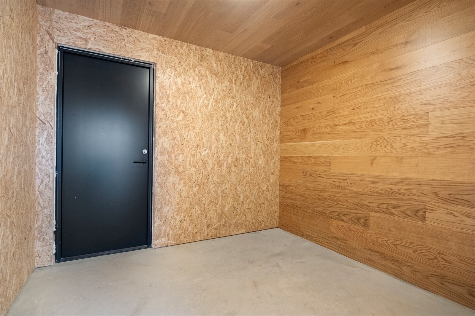 Rommet har vegger av trepanel og OSB-plater, samt et betonggulv som gir en solid base. Galleribilde