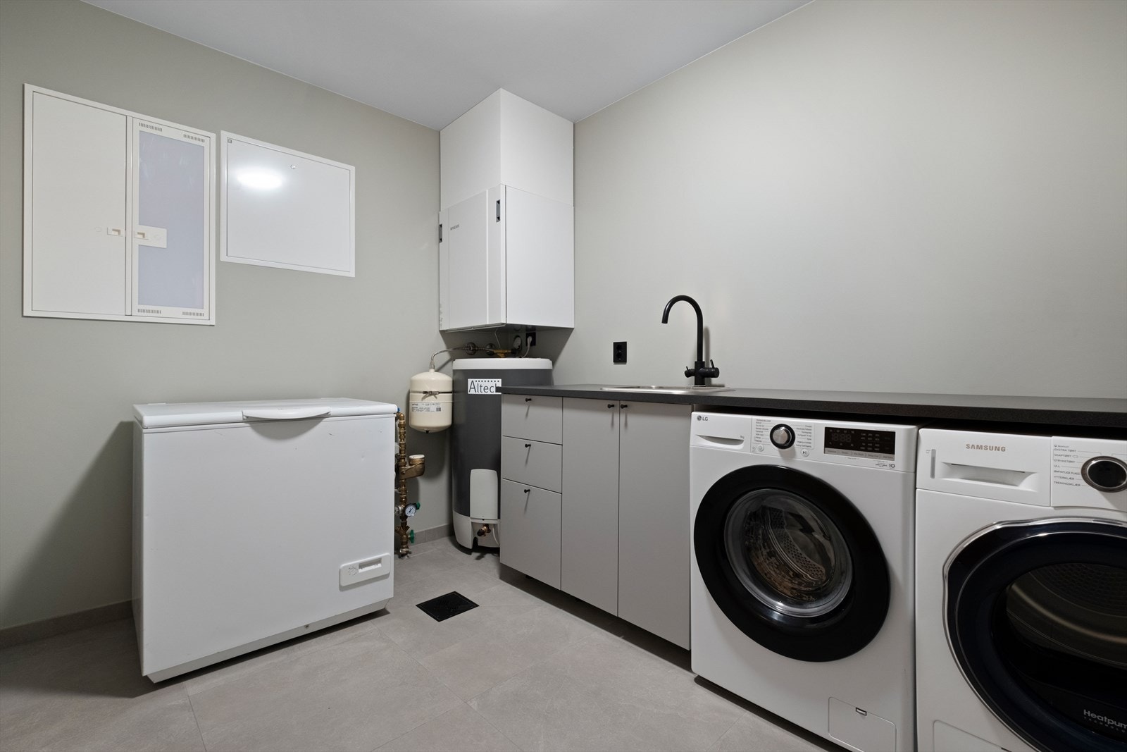 Rommet har benkeplate med vask og skap for oppbevaring, samt en stor fryseboks. Galleribilde