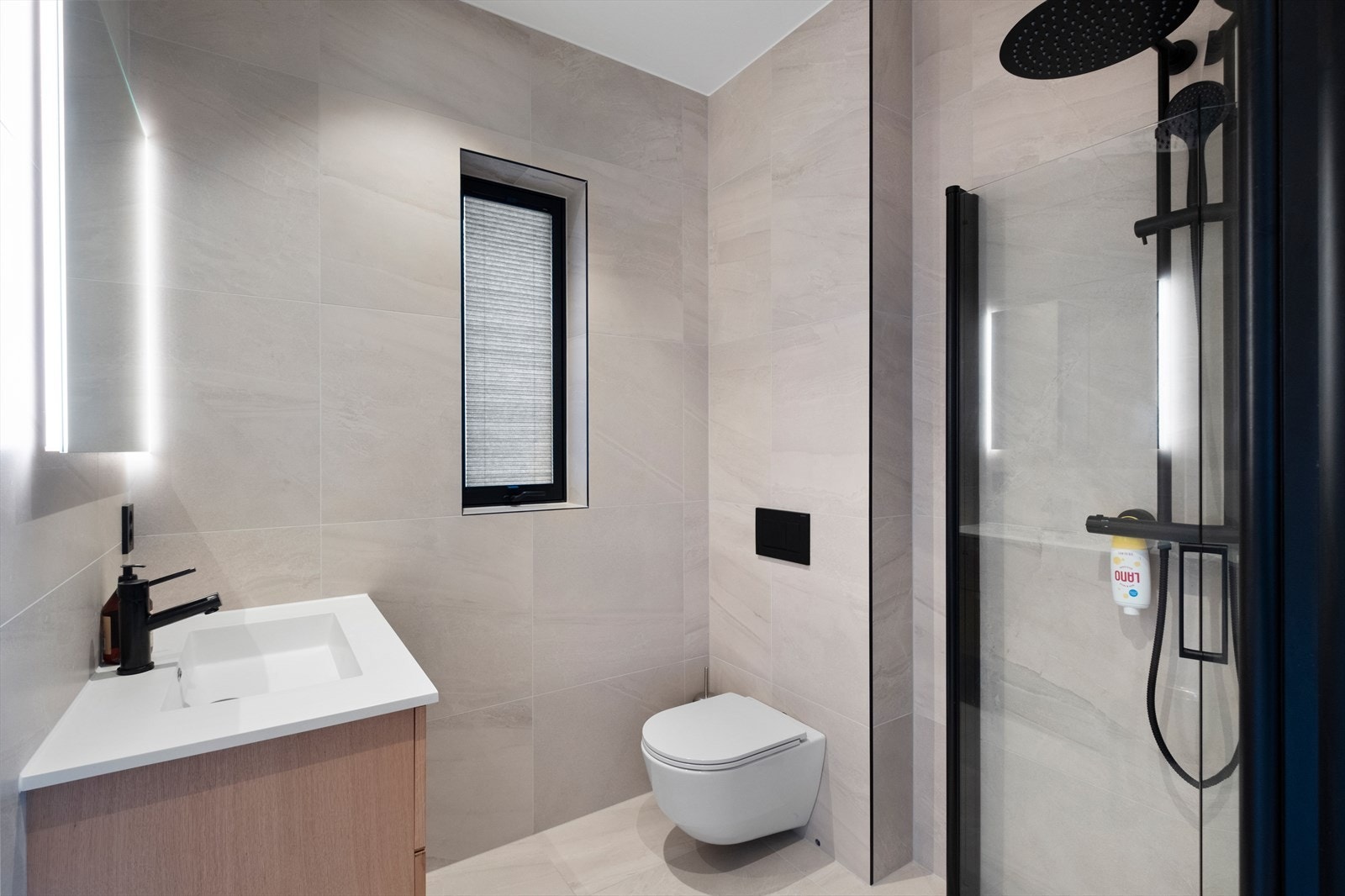 Flislagte vegger og gulv gir et stilrent uttrykk på badet tilknyttet hovedsoverommet. Galleribilde