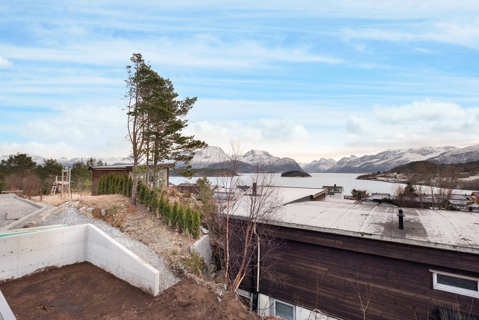 Terrenget er variert med beplantning og utsikt mot fjorden. Galleribilde