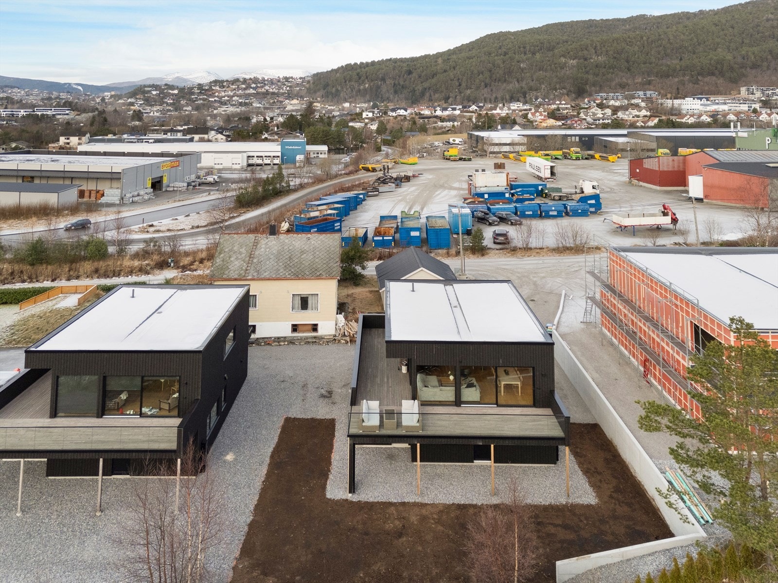 Boligen har en moderne arkitektur med flatt tak og mørk fasade. Galleribilde