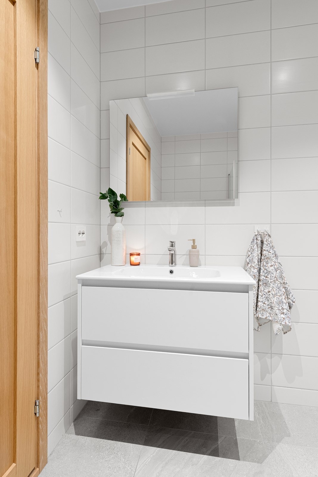 Innredning med skuffer og ovenpåliggende servant med ett-greps armatur. Speil med lys og stikkontakt over servant Galleribilde