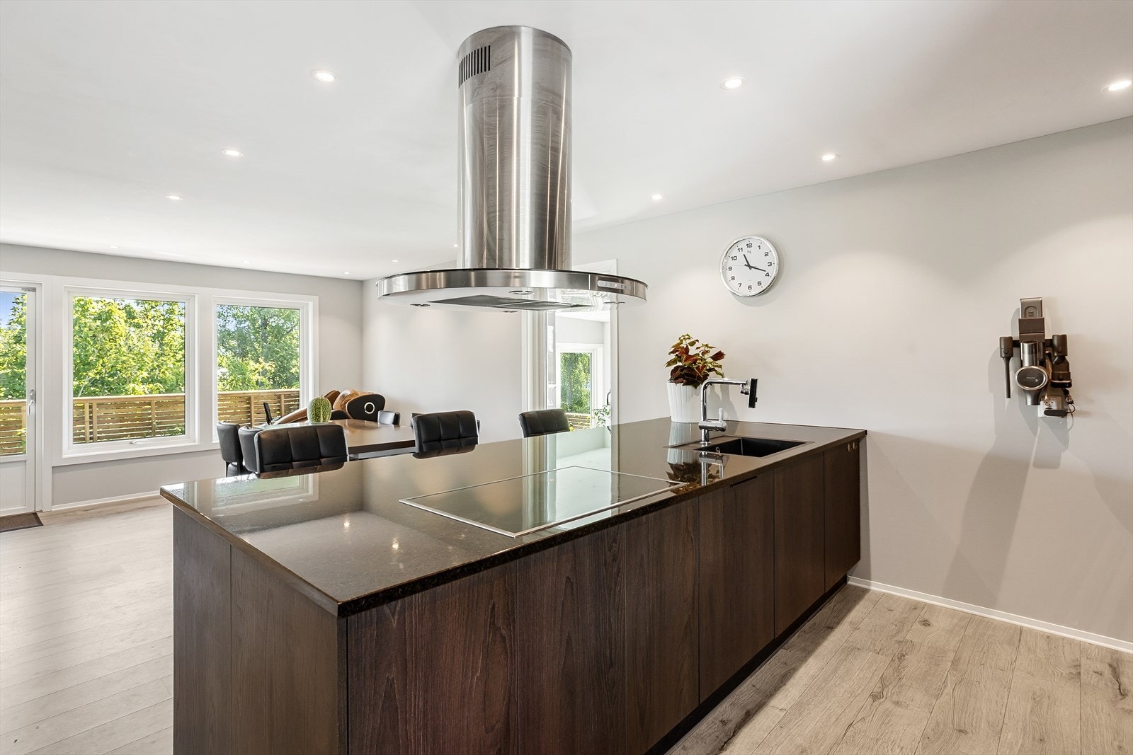 Moderne kjøkken med stor øy, platetopp og fritthengende ventilator i stål. Galleribilde