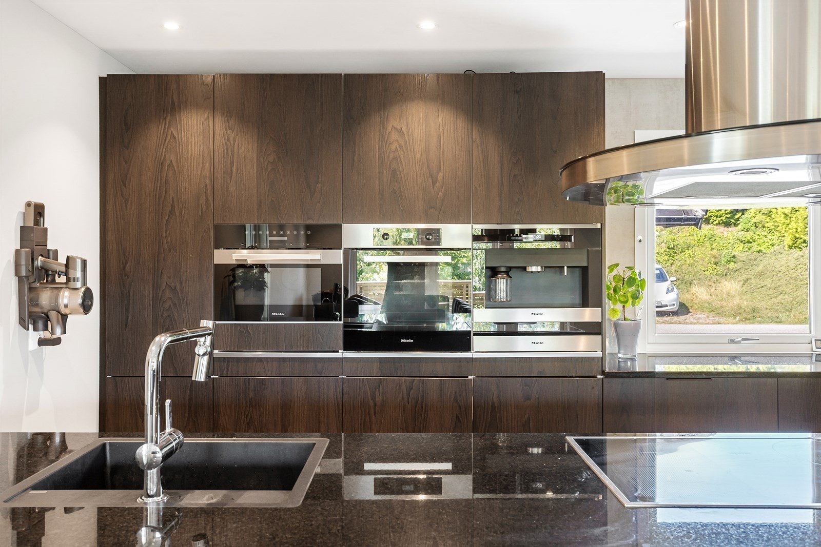 Eksklusivt kjøkken med mørke trefronter og integrerte hvitevarer. Galleribilde