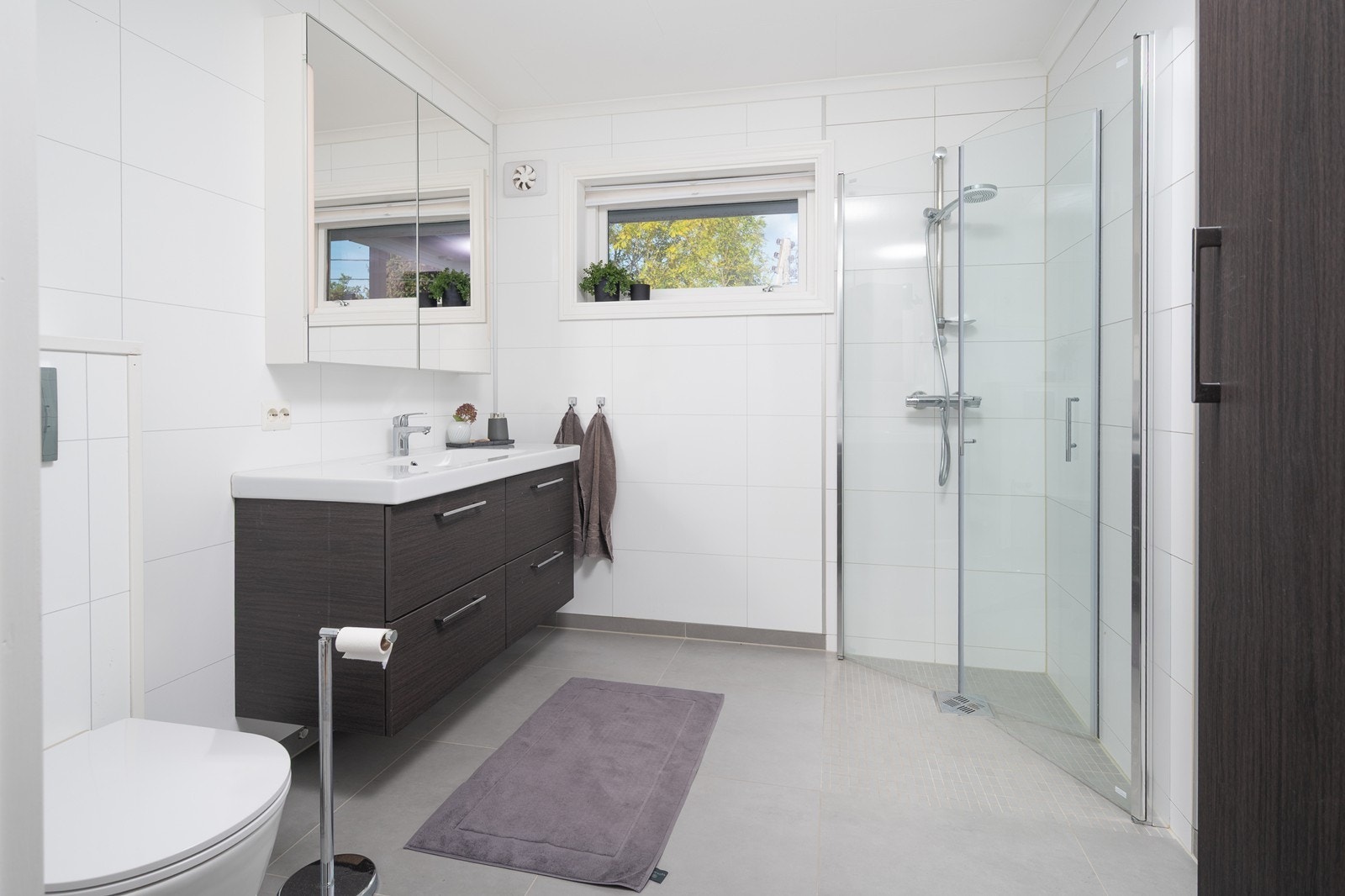 Renovert bad med varmekabler, vegghengt wc, dusj og stilren innredning Galleribilde