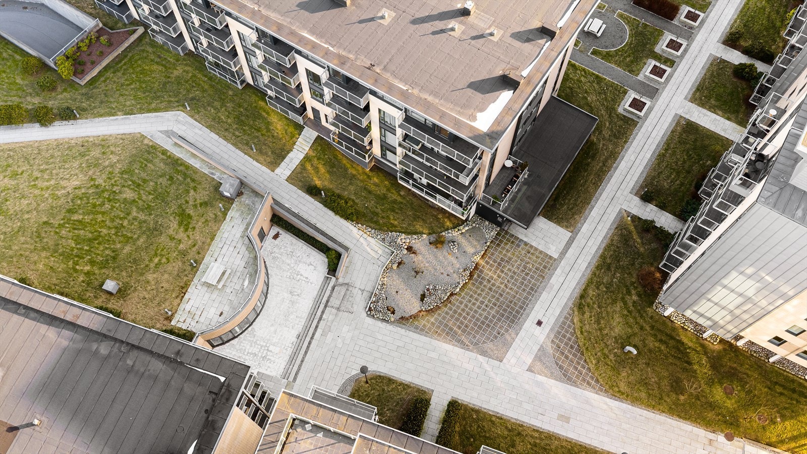 Fellesareal og tomt med utsmykninger i stein, gressplen, flott beplanting og lang kaipromenade Galleribilde