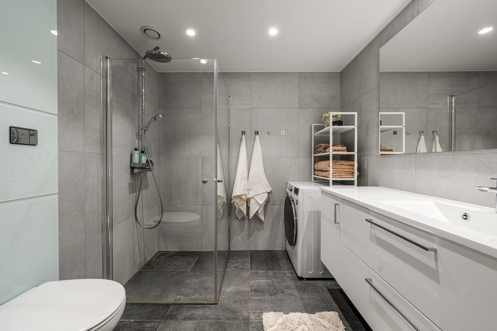 Lekkert baderom med moderne flisvalg, elektriske varmekabler og spotter i tak. Galleribilde