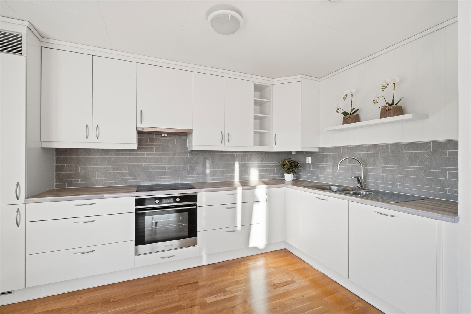 Kjøkkeninnredning med glatte, hvite fronter og integrerte hvitevarer. Galleribilde