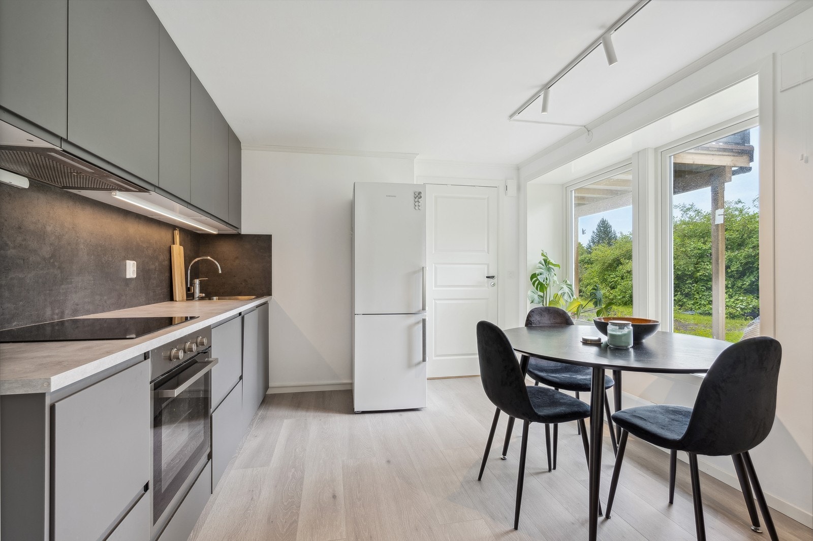 Stilrent kjøkken med integrert stekeovn, platetopp, oppvaskmaskin samt frittstående kombiskap. Galleribilde